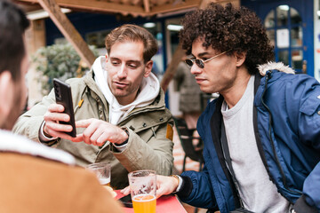 four multi ethnic friends drinking beers and talking