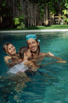 Young couple mom and dad with a child playing in the pool.