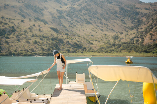 Young woman on dock getting onto pedal boat on Lake Kournas in Crete