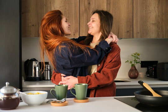 Lesbian happy couple hugging in love together in kitchen.