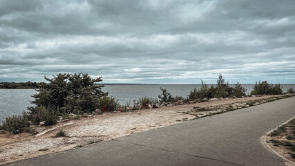 View of the road, bay and low gray clouds on a cloudy summer day. - Powered by Adobe