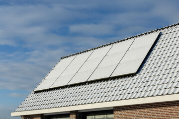 Fototapeta premium Utrecht, the Netherlands. 19 January 2024. Private solar panels with snow on a detached bungalow family house on the roof in the winter.