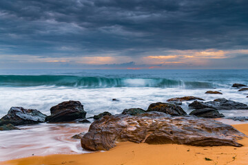 Sunrise at the seaside with rocks and beautiful diffused light by the rain clouds