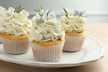 Tasty Easter cupcakes with vanilla cream on wooden table, closeup