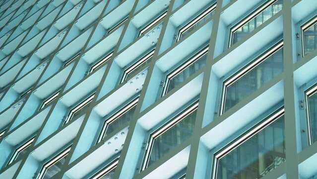 Handheld shot of cool artsy windows of the Public Library in Seattle, Washington USA that create abstract lines and grids with an industrial style of exposed bolts and a blue greenish hue.