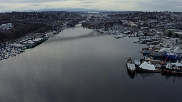 Dolly in tilt up aerial drone shot revealing the Aurora bridge in Seattle, Washington that spans over the Lake Union Marina with busy traffic on a cold overcast spring evening