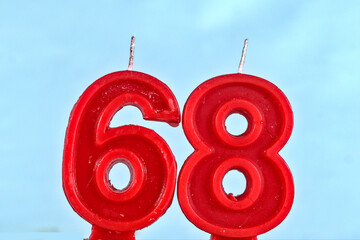 close up on red number sixty eighth birthday candle on a white background.
