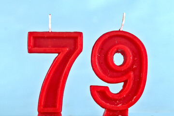 close up on a red number seventy ninth birthday candle on a white background.
