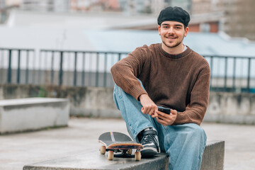 young man on the street with mobile phone and skateboard