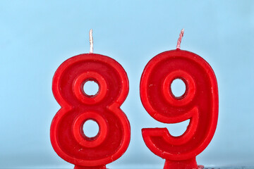 close up on a red number eighty ninth birthday candle on a white background.
