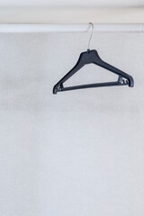 A clothes hanger hangs on a white crossbar.