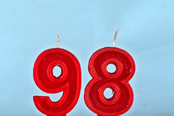 close up on a red number ninety eighth birthday candle on a white background.

