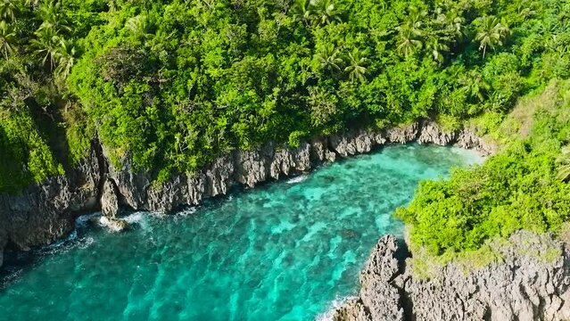 Waves crashing on rocky coastal with turquoise sea water and corals. San Jose Island. Romblon, Philippines.