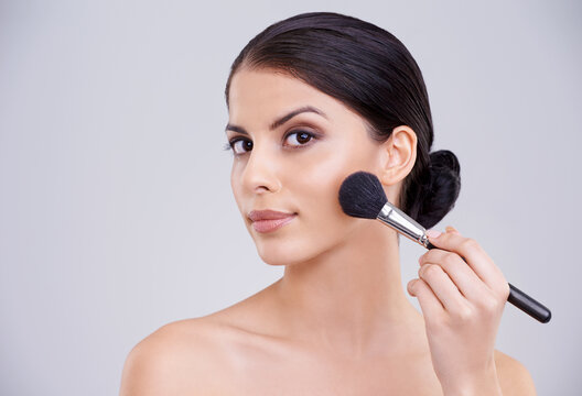 Woman, portrait and makeup application or brush in studio for beauty blush, cosmetics or grey background. Male person, face and treatment transformation for makeover wellness, mockup space or routine