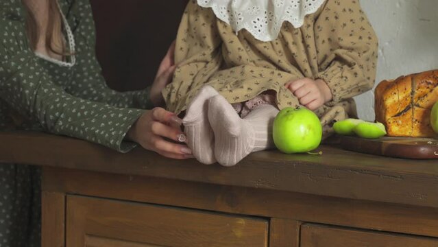 A teenage girl tickles her little sister's heels. Close-up.