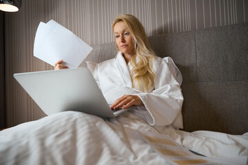Female entrepreneur working on her portable computer in hotel room