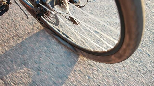 A punctured rear wheel of a bicycle riding on an asphalt road, close-up. Slow motion