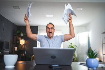 Middle aged Caucasian man going crazy from doing paperwork at home