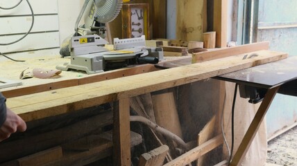 homemade circular saw in the form of a folding table with a sharp disk for sawing wood material in a carpenter's workshop, cutting a wide board into two parts on a circular saw