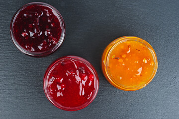 Three colored jam in glass jare isolated on a black background