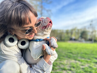 happy hipster woman playing with bulldog in the park , spring and summer vacation. stylish girl with funny dog resting, hugging, singing and having fun in sun, cute moments. space for text