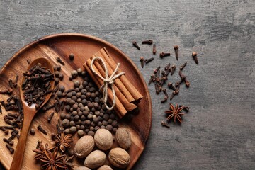 Different spices and nuts on gray textured table, top view. Space for text