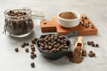 Aromatic allspice pepper grains and powder on grey table