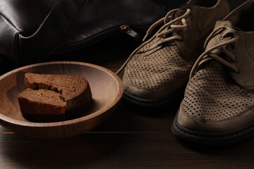 Poverty. Old shoes, bag and pieces of bread on wooden table