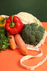 String bag with fresh vegetables on color background