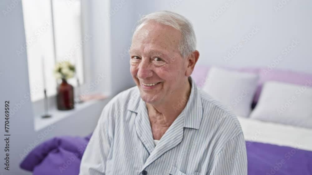 Poster Cheerful senior man in pyjamas winking with sexy expression on his happy face, sitting on his bed looking at the camera in his cozy bedroom.