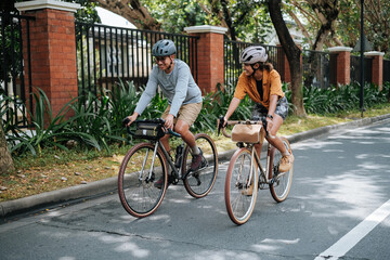 A young couple riding their bicycles in the summer.