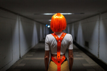 Beautiful woman in a futuristic suit with orange hair on a dark background. Augmented reality,...