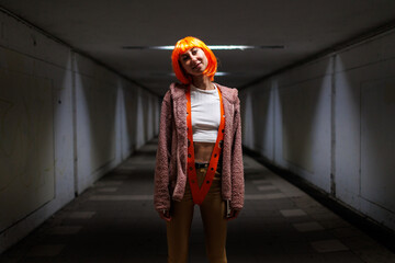 Beautiful woman in a futuristic suit with orange hair on a dark background. Augmented reality,...
