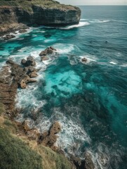 Rocky coast with blue water, stone. Coast covered with green grass. Water crystal clear, has beautiful blue-green color. Stone in water large, has rough texture. Waves crashing against coast.