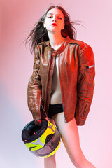 One Sexy Caucasian Female Motorcyclist Posing In Leather Protective Jacket And Helmet Over Yellow Background. - 770484151