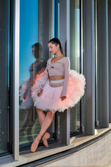 Dance Sport Ideas. Winsome Sexy Slim Professional Caucasian Ballet Dancer in Pink Tutu Dress Standing Against Metal Glass Construction In Stretching Pose
