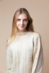 Smiling Winsome Caucasian Blond Female Wearing Knitter Decorated Warm Sweater Over Beige Background - 770484773