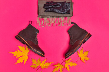 View of Premium Dark Brown Grain Brogue Derby Boots Made of Calf Leather with Rubber Sole Placed With Maple Leaves and Scarf With Gloves Over Burgundy. - 770485561