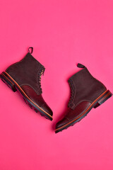 Flatlay View of Dark Brown Grain Brogue Derby Boots Made of Calf Leather with Rubber Sole Placed Over Pink Burgundy Background. - 770485569