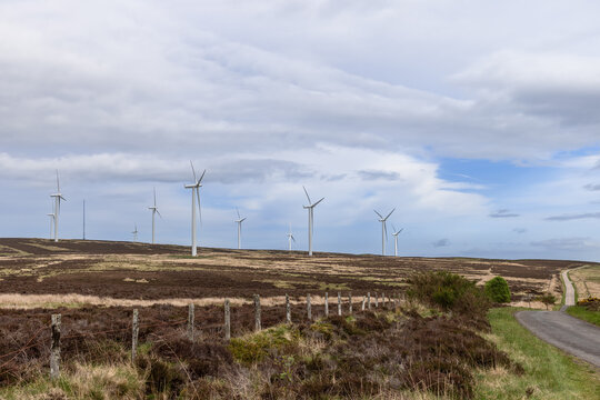 In Scotland, a journey along a solitary road reveals view of wind turbines, symbolizing the harmonious blend of natural beauty and the forefront of green technology