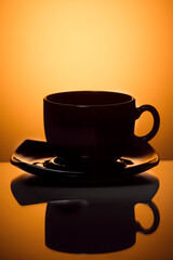 Set of Glass Teacup With Plate isolated Over Glowing Orange Gradient Background