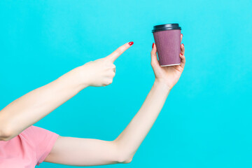 Closeup of Female Girl Hand Pointing with Finger Cup of Coffee Drink Isolated on Vivid Trendy Turquoise - 770488310