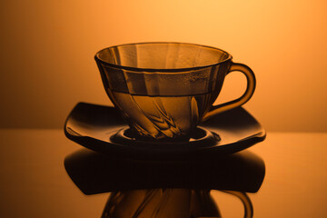 Set of Glass Teacup With Plate isolated Over Glowing Orange Gradient Background. - 770488326