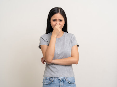 Bad smell stinks. Young beautiful asian woman pinching nose with disgust. Holding breath with fingers on nose