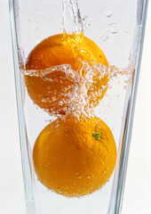 Fresh orange in clear water glass - obrazy, fototapety, plakaty