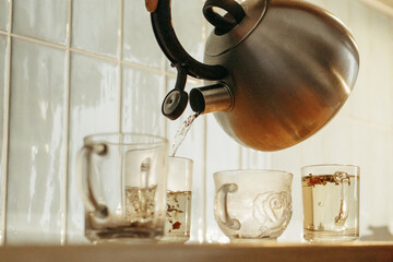 Tea Kettle Pouring Water Into Glasses on Counter