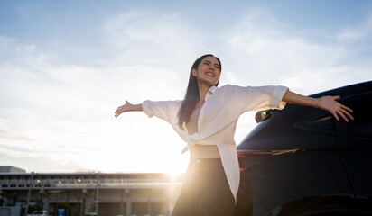 Young beautiful asian women buying new car. she was standing near car on the roadside. Beautiful moment blue sky Smiling female driving travel by vehicle on the road on a bright day with sun light.