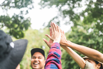Group of young traveller people giving high five for friendship while camping in nature trip. Happy...