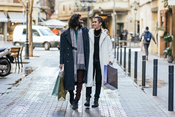 Gay couple walking on the street with shopping bags. - obrazy, fototapety, plakaty