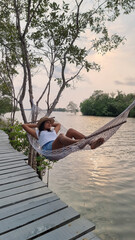 A woman relaxes in a hammock on a dock, enjoying the peaceful waters and gentle breeze on a sunny day